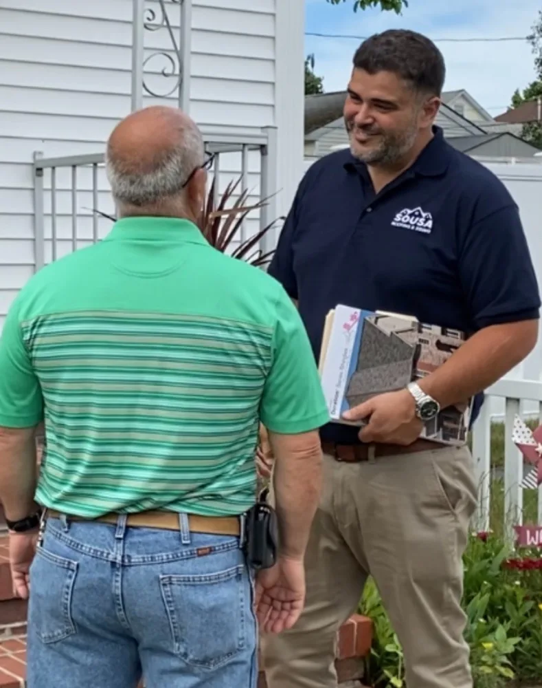 Jaime DeSousa, owner of Sousa Roofing & Construction, reviewing shingle samples with a homeowner