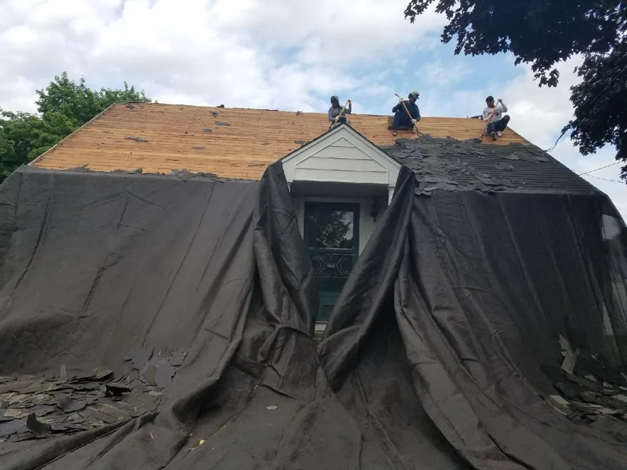 Roofing crew tearing off old shingles during a roof replacement